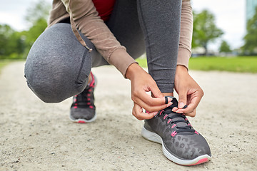 Image showing close up of woman tying shoelaces outdoors