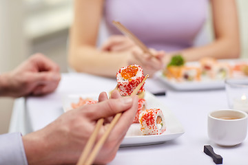 Image showing close up of couple eating sushi at restaurant