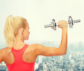 Image showing sporty woman with heavy steel dumbbell from back