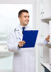 Image showing happy doctor with clipboard in medical office