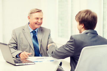 Image showing older man and young man shaking hands in office