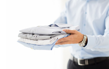 Image showing close up of businessman holding folded shirts