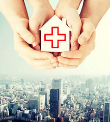 Image showing hands holding paper house with red cross