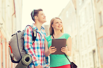 Image showing smiling couple with tablet pc and backpack in city