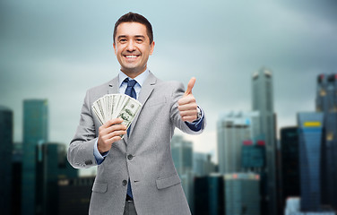 Image showing smiling businessman with money showing thumbs up
