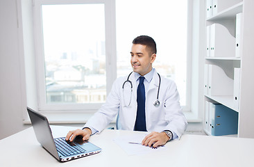 Image showing smiling male doctor with laptop in medical office
