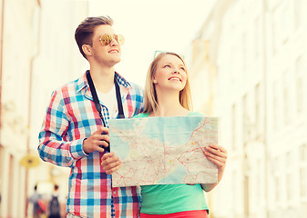 Image showing smiling couple with map and photo camera in city