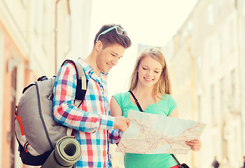 Image showing smiling couple with map and backpack in city