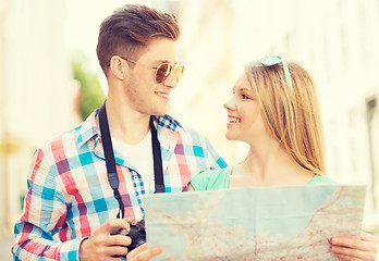 Image showing smiling couple with map and photo camera in city