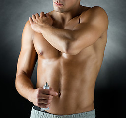 Image showing young male bodybuilder applying pain relief gel
