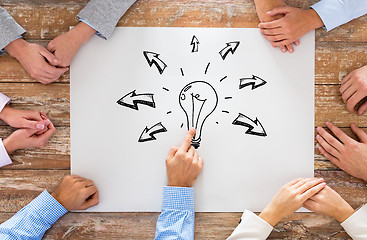Image showing close up of business team pointing to bulb doodle