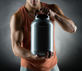 Image showing young male bodybuilder holding jar with protein