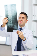 Image showing smiling male doctor in white coat looking at x-ray