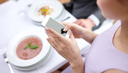 Image showing close up of couple with smartphones at restaurant