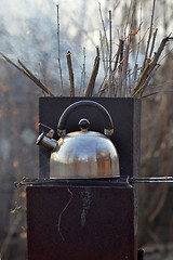 Image showing the whistling kettle begins to boil on a brazier.
