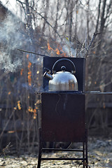 Image showing the whistling kettle begins to boil on a brazier