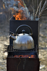 Image showing the whistling kettle begins to boil on a brazier.