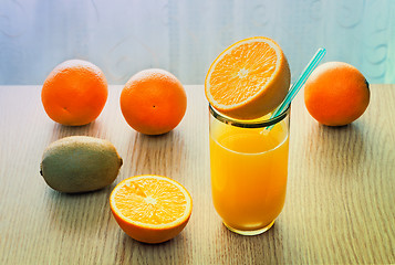 Image showing Orange juice in a glass and oranges on the table.