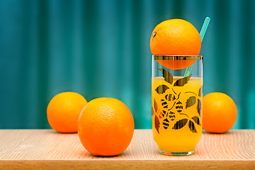 Image showing Orange juice in a glass and oranges on the table.