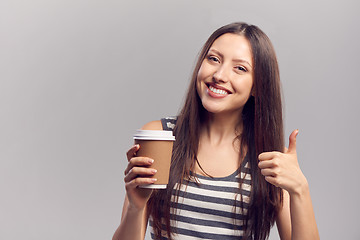 Image showing Woman drinking hot drink from disposable paper cup