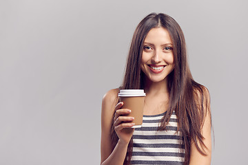 Image showing Woman drinking hot drink from disposable paper cup