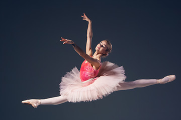 Image showing Beautiful female ballet dancer on a grey background. Ballerina is wearing  pink tutu and pointe shoes.