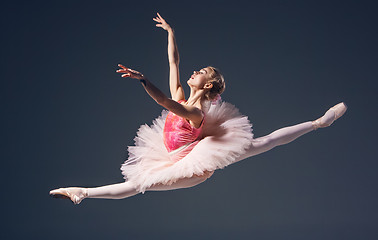 Image showing Beautiful female ballet dancer on a grey background. Ballerina is wearing  pink tutu and pointe shoes.