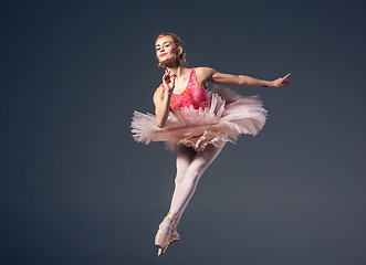 Image showing Beautiful female ballet dancer on a grey background. Ballerina is wearing  pink tutu and pointe shoes.