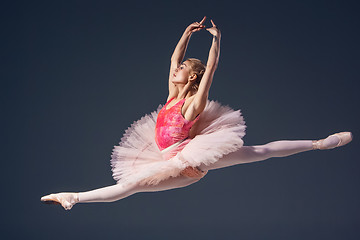 Image showing Beautiful female ballet dancer on a grey background. Ballerina is wearing  pink tutu and pointe shoes.