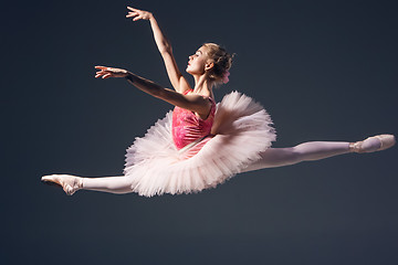 Image showing Beautiful female ballet dancer on a grey background. Ballerina is wearing  pink tutu and pointe shoes.