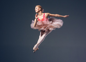 Image showing Beautiful female ballet dancer on a grey background. Ballerina is wearing  pink tutu and pointe shoes.