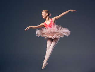 Image showing Beautiful female ballet dancer on a grey background. Ballerina is wearing  pink tutu and pointe shoes.