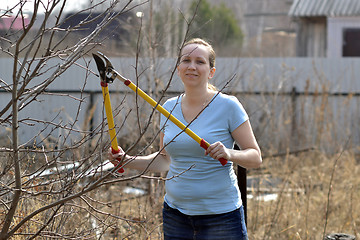 Image showing The woman in a garden cuts off branches secateurs with long hand