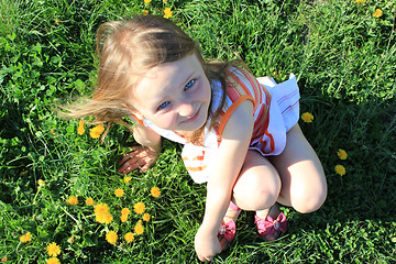 Image showing little girl lying on the grass with dandelions