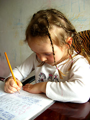 Image showing schoolgirl learns lessons at the table