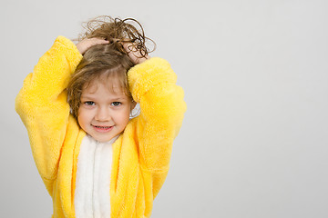 Image showing Cheerful girl in yellow bathrobe holding hair