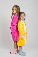 Image showing Two girls in dressing gowns stand back to back 