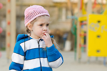 Image showing Girl sucks a finger on the playground