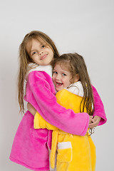 Image showing Girls in pink and yellow robe hug