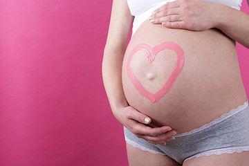 Image showing Closeup of a pregnant woman with pink heart on her belly