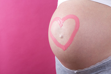 Image showing Closeup of a pregnant woman with pink heart on her belly