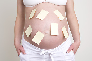 Image showing Pregnant woman with lots of yellow labels on her belly