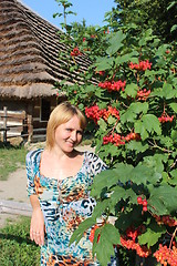 Image showing girl with red guelder-rose besides an rural house