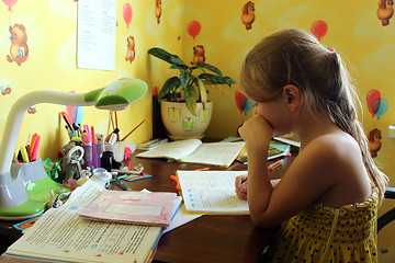 Image showing schoolgirl learns lessons at the table