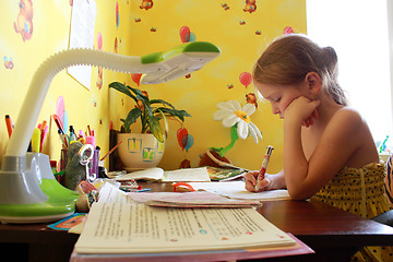 Image showing schoolgirl learns lessons at the table