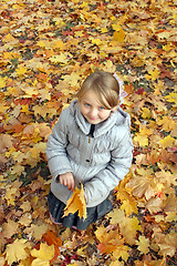 Image showing little girl with yellow leaves in the park