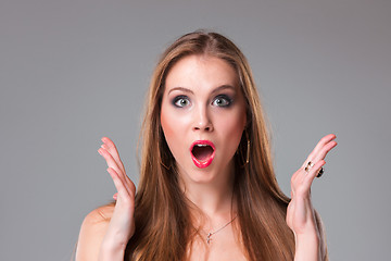 Image showing Close-up portrait of surprised beautiful girl holding her head in amazement and open-mouthed.