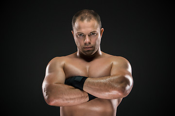 Image showing studio portrait of young caucasian boxer with folded hands posing ark background