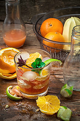 Image showing fresh juice of tropical citrus fruits on wooden background
