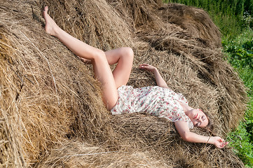 Image showing Young pretty woman relaxes on hay